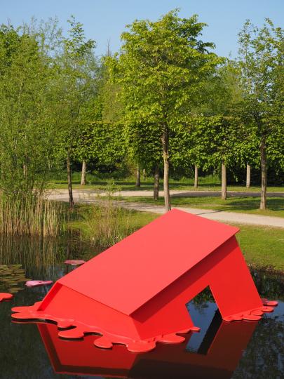 Photo d'un parc avec une marre - étang  et une maison rouge en métal qui coule