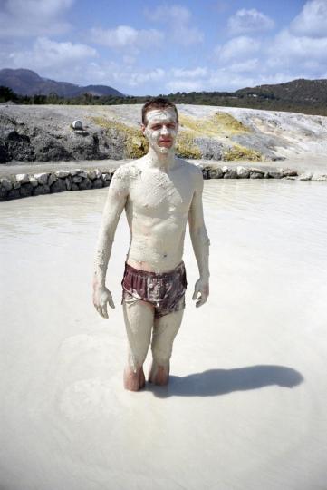 photo d'un homme les jambes dans une marre d'eau grise avec une espèce de plâtre gris sur tout le corps