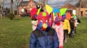 groupe d'enfants en file avec un masque se carnaval et un tambour dans une prairie